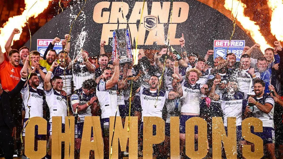 Wakefield lift the Super League trophy with 'CHAMPIONS' in front of them and a big gold GRAND FINAL arch behind them