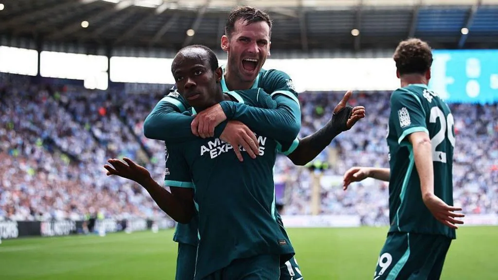 Brighton's Malick Yalcouye make a shrugging action in celebration, while being mobbed by Brighton team-mate Pascal Gross