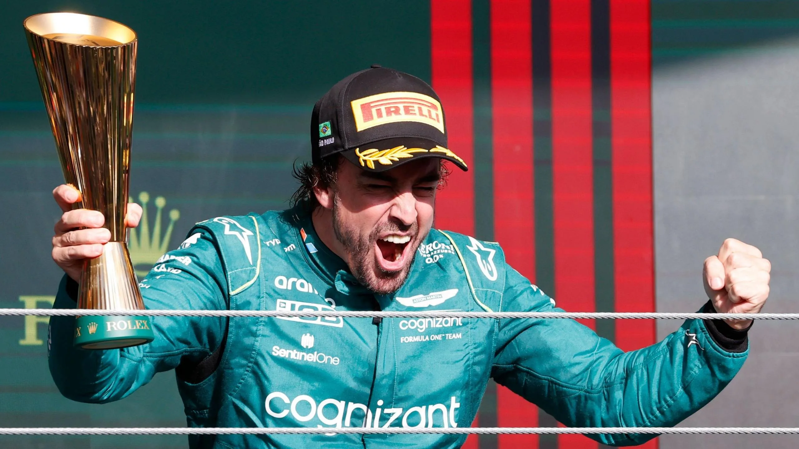 Fernando Alonso clenches his fists in celebration while holding a trophy after finishing third in the 2023 Sao Paulo Grand Prix
