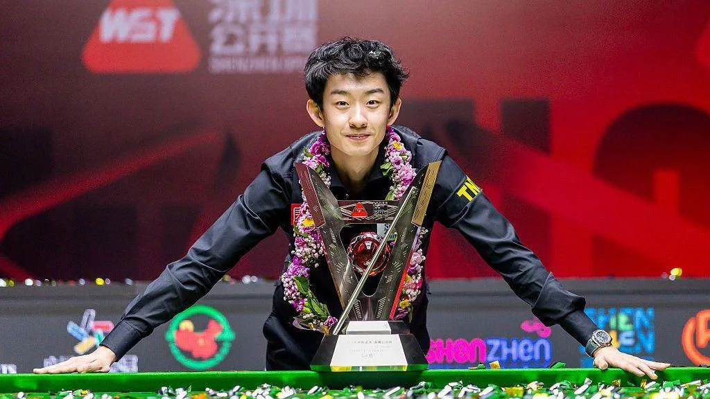 Wu Yize poses with the Shenzhen Open trophy with ticker tape on the table after his victory in the final