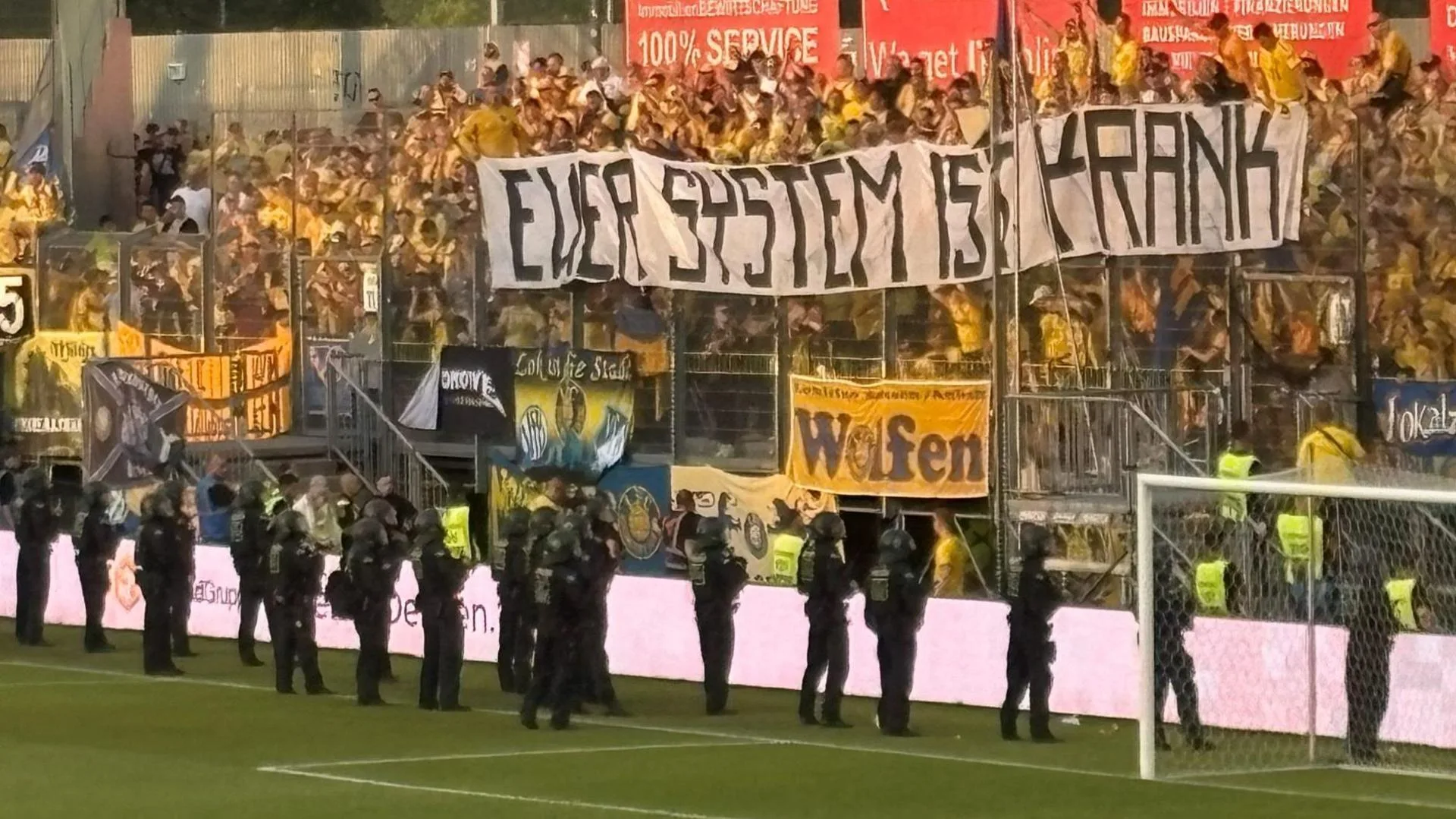 Fans hold a banner that says 'Euer System ist krank' or 'your system is sick'