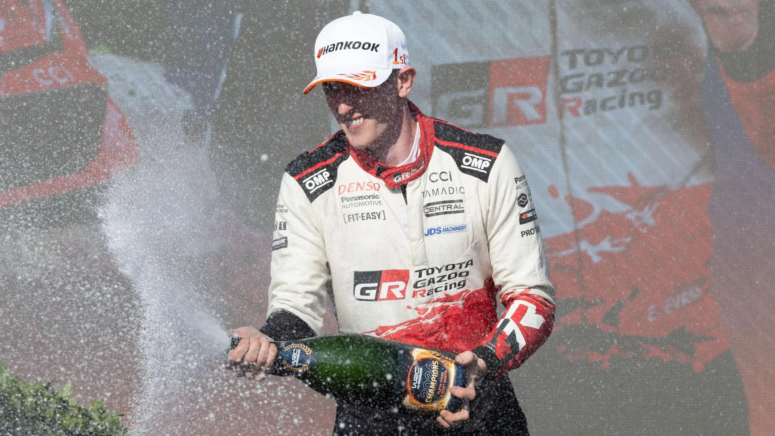 Elfyn Evans sprays champagne on the podium