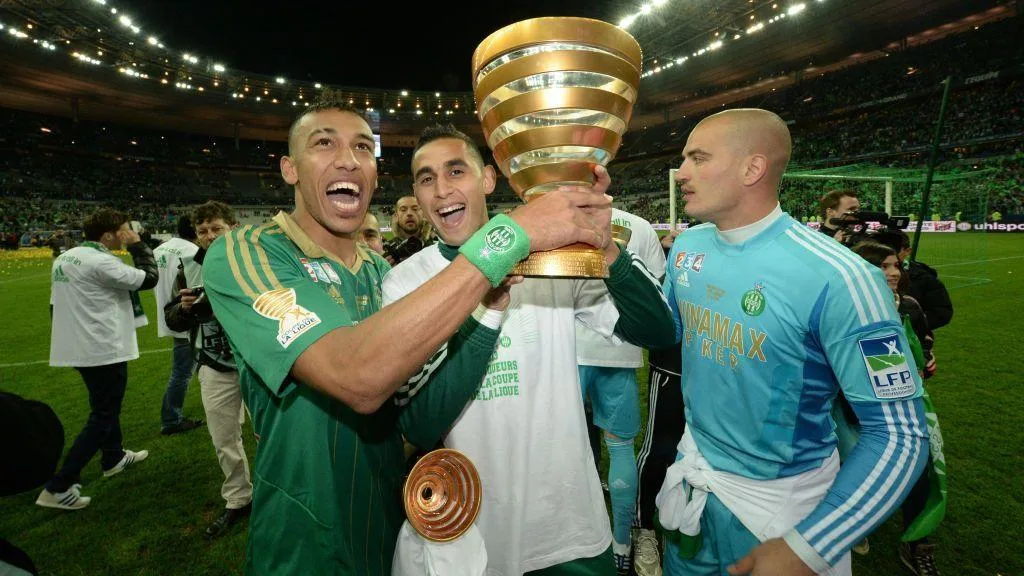 A smiling Pierre-Emerick Aubameyang celebrates as he holds up a trophy