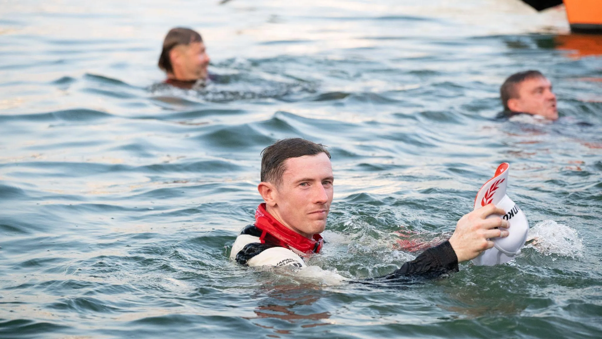 Elfyn Evans in full overalls in the sea holding his hat