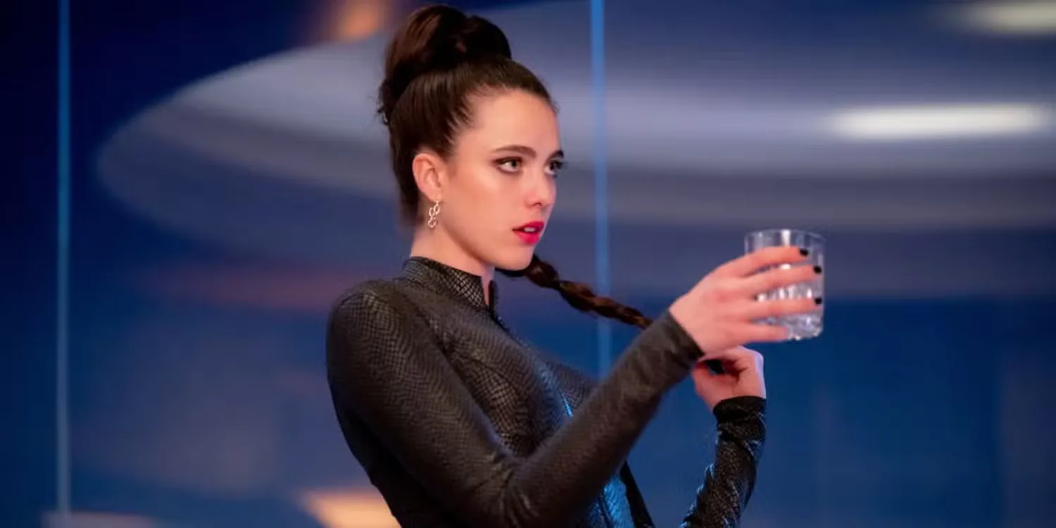Margaret Qualley as Sue holding a drink inside a strange-looking room while looking stylish in The Substance (2024)