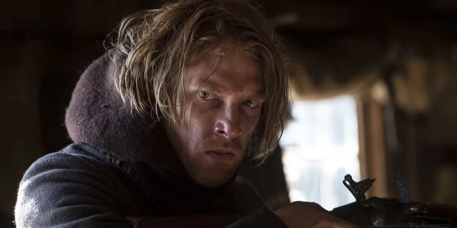 Domhnall Gleeson holding a rifle and looking serious in The Revenant.