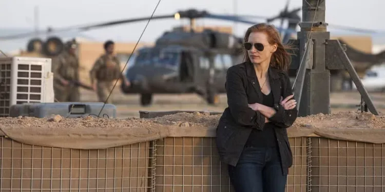 Maya leaning back agaisnt a fence while looking to her right in Zero Dark Thirty