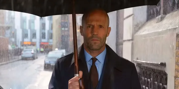 Jason Statham standing under an umbrella in 'Hobbs & Shaw'
