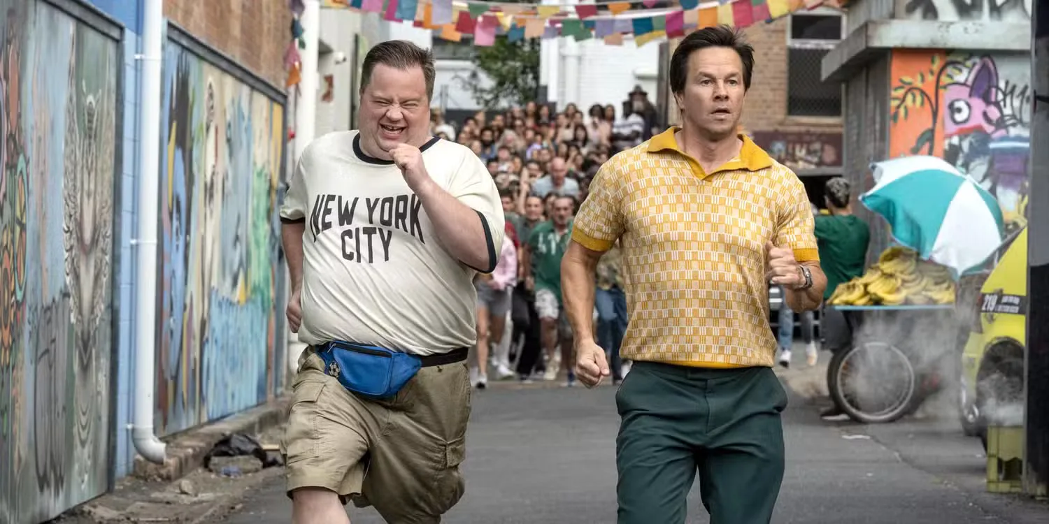 Elijah and Brad run through the streets as a mob of people chase after them.