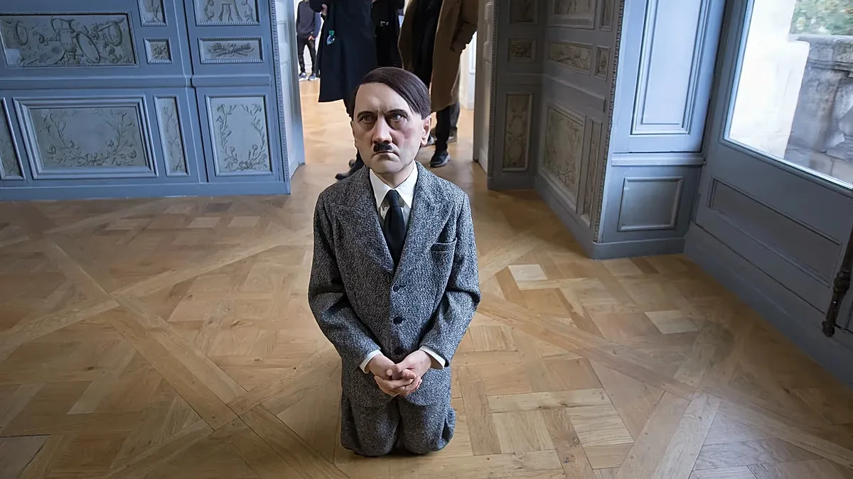 Visitors looks at "him", a controversial sculpture of Adolf Hitler, an art installation by Maurizio Cattelan.