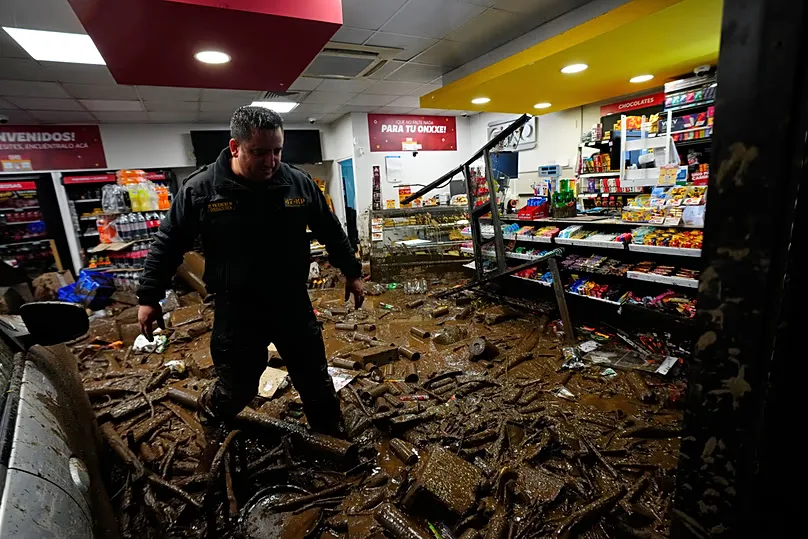 A rescue worker walks through muddy debris in a shop damaged by flash flooding caused by heavy rains in the Las Condes district of Santiago, Chile, Thursday, Oct. 8, 2026