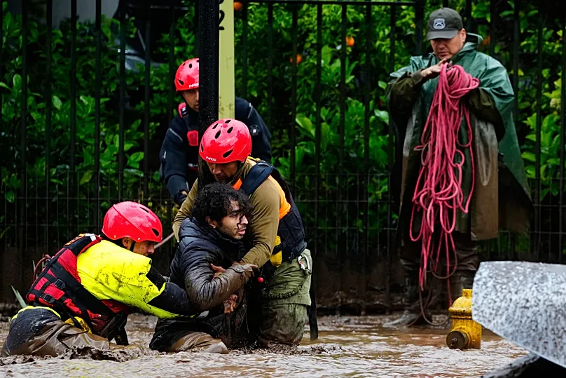 A man is pulled to safety by rescue workers after heavy rains caused flash flooding in the Las Condes district of Santiago, Chile, Thursday, Oct. 8, 2026