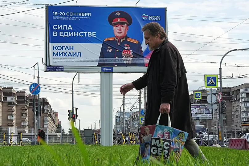 In Saint Petersburg a man walks past a billboard urging people to vote for a candidate from the United Russia party