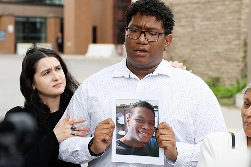 Ethan Mitchell holds a photograph of his brother, Stephen Mitchell Jr outside court after Law admitted to 14 counts of assisting suicide. 29 May, 2026.