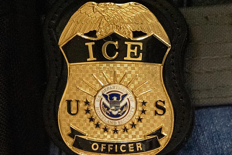 FILE - A federal agent wears an Immigration and Customs Enforcement badge in New York, June 10, 2025