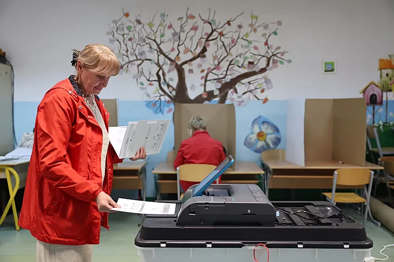 A woman places her ballot into an electronic ballot box during the general election in Sarajevo, Bosnia, Sunday, Oct. 4, 2026. (AP Photo/Armin Durgut)