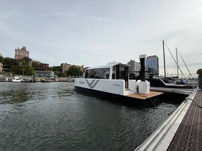 An electric ferry sits docked at a pier.